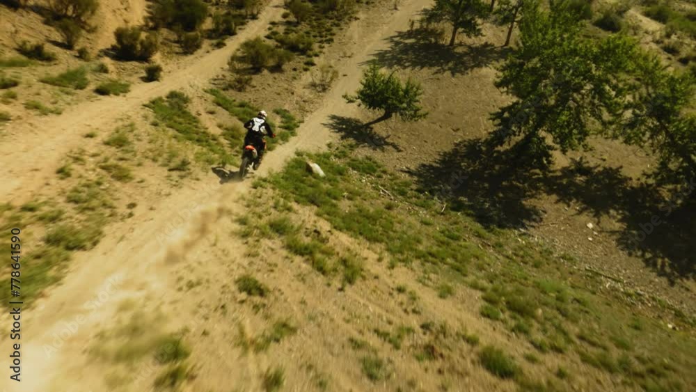 Motorbiker rides vehicle along ground road fpv drone. Extreme sportsman on motorcycle enjoys trip across hilly valley. Racing competition offroad Motorbiker rides vehicle along ground road fpv drone. Extreme sportsman on motorcycle enjoys trip across hilly valley. Racing competition offroad