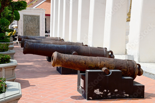 BANGKOK, THAILAND - April 11, 2024: The ancient black rusted cannon is located on the white wall In the museum at Thailand.