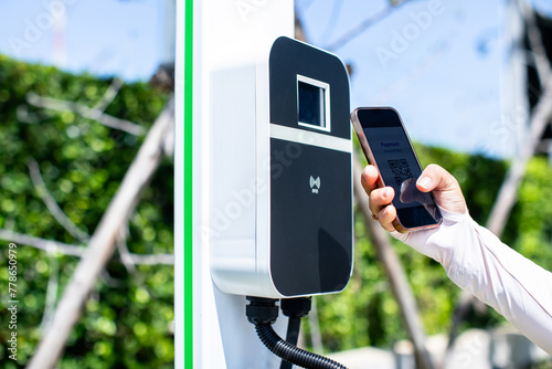 EV Driver use smartphone to scan QR Code on electric vehicle charging stations to pay for electricity. The concept of QR scanning payment instead of cash.