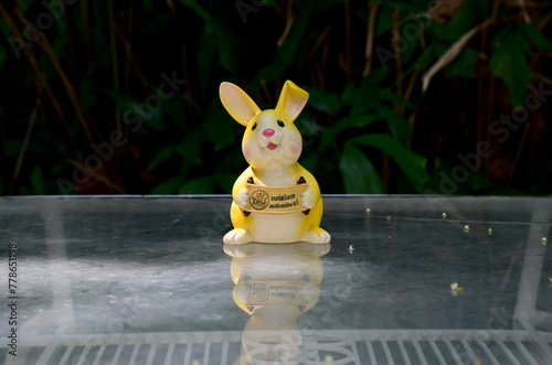 BANGKOK, THAILAND - April 16, 2024: Yellow Rabbit Piggy Bank holds sign 