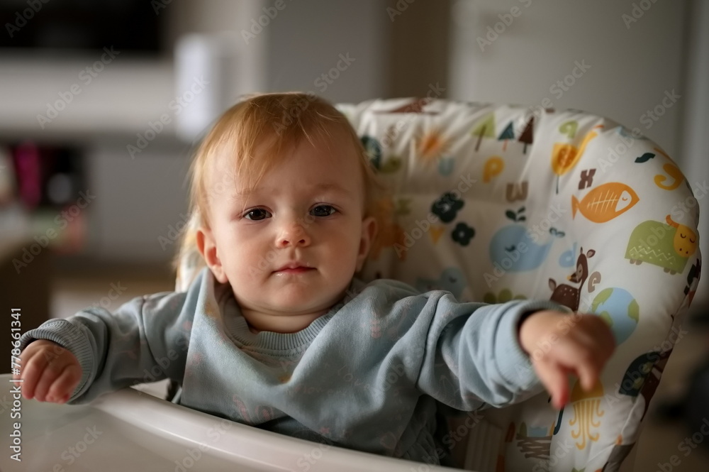Naklejka premium Adorable little baby girl sitting in high chair