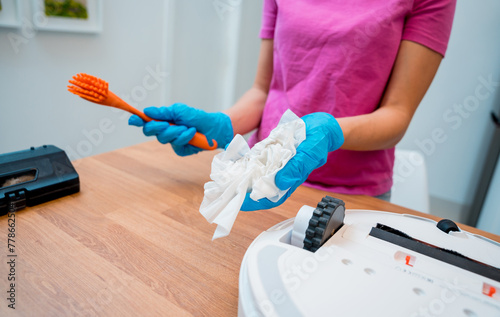 Wallpaper Mural A young woman cleans a robot vacuum cleaner from dirt after cleaning. Torontodigital.ca