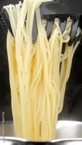 Cooking pasta in boiling water. Chef takes spaghetti out of the boiling water