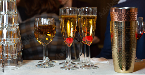 Champagne and Cocktails Ready for Guests. An elegant display of drinks including champagne flutes with cherries and a wine glass, all beautifully arranged on a table with a cocktail shaker in view.