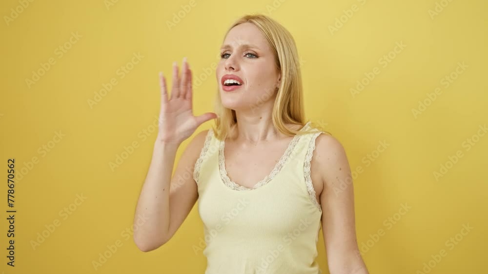 Blonde young woman wearing sleeveless t shirt standing clueless over yellow isolated background. arms open, baffled face, no idea, confused! Blonde young woman wearing sleeveless t shirt standing clueless over yellow isolated background. arms open, baffled face, no idea, confused!