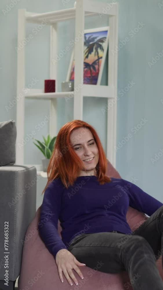 Red-haired housewife comes to sit on bean bag chair to rest after domestic chores. Happy woman enjoys relaxing in living room at home slow motion Red-haired housewife comes to sit on bean bag chair to rest after domestic chores. Happy woman enjoys relaxing in living room at home slow motion