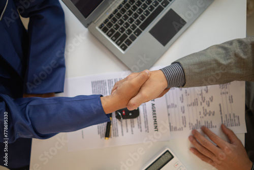customer and car dealer shake hands after agreeing to sales contract before making contract payment and handing over car keys to customer. concept of handshake between customers and car dealers.