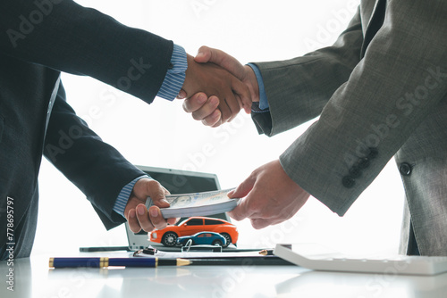 customer and car dealer shake hands after agreeing to sales contract before making contract payment and handing over car keys to customer. concept of handshake between customers and car dealers.