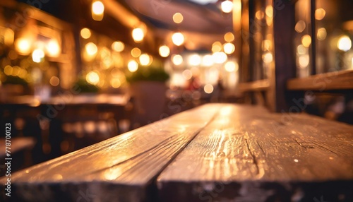 a wooden table is seen in the foreground with a blurred background created by the soft glow of restaurant lights the focus is on the texture and simplicity of the table against the abstract backdrop photo
