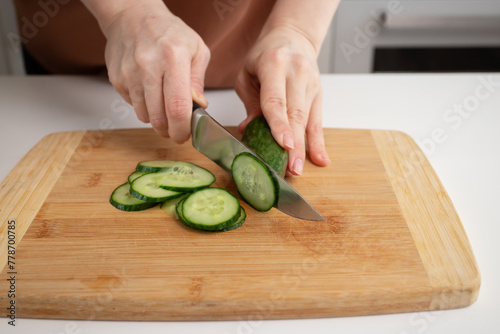 Close-up of woman cutting cucumbers, kitchen cooking, vegetable slicing, healthy meal preparation