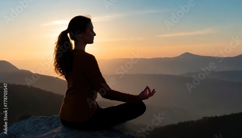 A silhouette of a woman meditating on a mountaintop during sunset. The serene landscape reveals a gradient sky and layers of distant mountains 