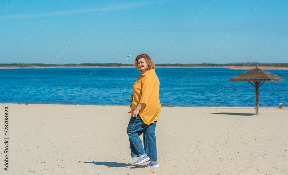 Vacation mood. Plus size happy mature lady wear yellow shirt and blue pants at beach , spring - summer clothes collection Vacation mood. Plus size happy mature lady wear yellow shirt and blue pants at beach , spring - summer clothes collection