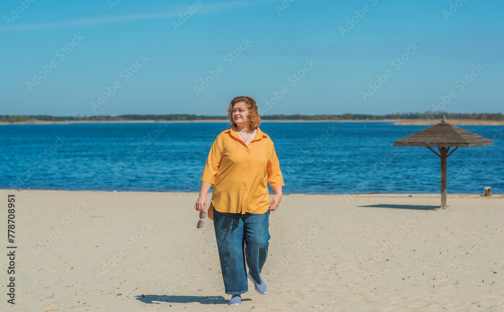 Vacation mood. Plus size happy mature lady wear yellow shirt and blue pants at beach , spring - summer clothes collection Vacation mood. Plus size happy mature lady wear yellow shirt and blue pants at beach , spring - summer clothes collection