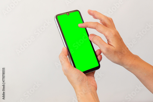 women hand holding smart mobile phone with blank green screen on isolated white background