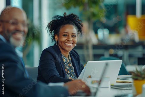 young smiling african american female business CEO sitting at desk with laptop and senior male together looking happy while working on financial data, meeting in modern office. generative AI