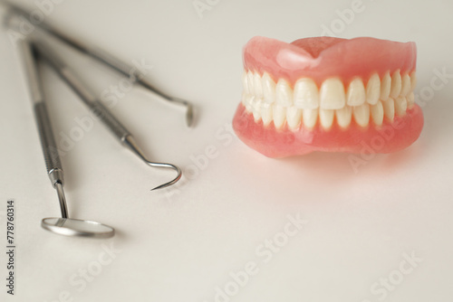 Dentures and dentist tools on a white background with copy space