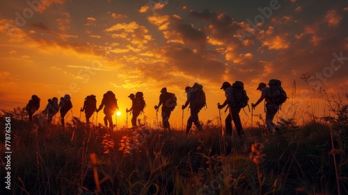 A group of soldiers are walking in a field at sunset. The sun is setting behind them, casting a warm glow over the scene. The soldiers are wearing backpacks and appear to be on a long journey