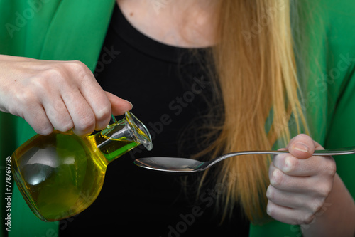 Kobieta pije olej, nalewać olej na łyżeczkę 