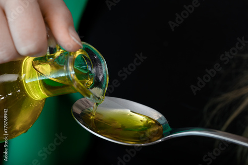Swieży olej tloczony z nasion czarnuszki siewnej nalewany na łyżeczkę z bliska