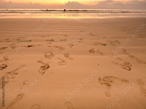 Many leaving footprint on sand beach with sunset sky background. Close-up many people's footprints from foot step walking variety direction on the wet sand. Beach travel, summer background concept.