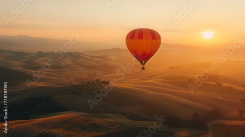 A hot air balloon ascending at sunrise over rolling hills © paisorn