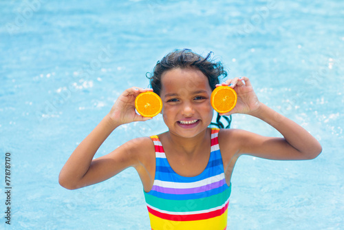 Child with orange in swimming pool