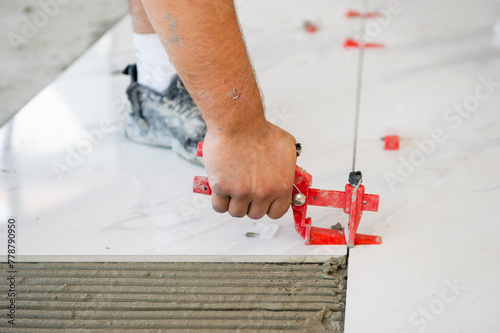 Ceramic white floor tiles laid over adhesive with a tile leveling system