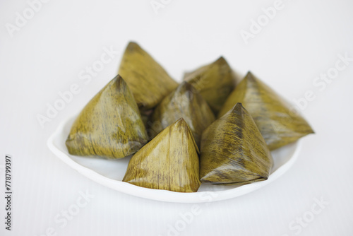 Bild auf Leinwand Sweet stuffed dough pyramid or Khanom Tian in Thai language, wrapped by banana leaf and streamed