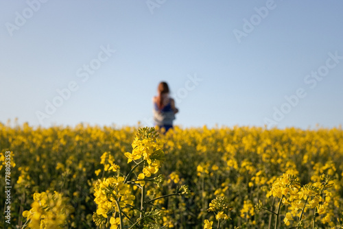 woman in the field. Rear view of woman standing amidst oilseed rape field against clear sky