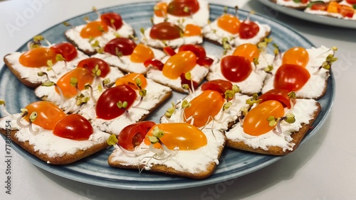 Close crackers spread with soft cottage cheese with cherry tomatoes cut in half and decorated with micro greens. side view. Snack for children. healthy food. holiday in kindergarten