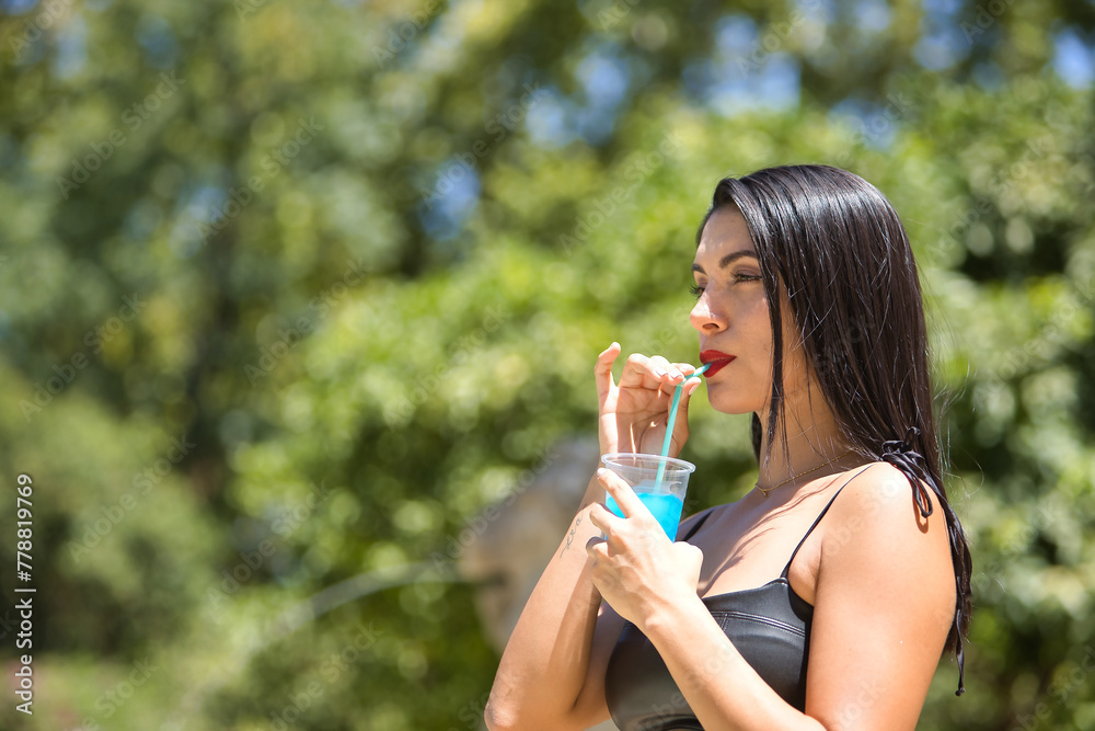 Portrait of South American woman, young, pretty, brunette with leather top, drinking a blue hailstorm with a straw. Concept beauty, diversity, beverages, heat, summer, ice cream. Portrait of South American woman, young, pretty, brunette with leather top, drinking a blue hailstorm with a straw. Concept beauty, diversity, beverages, heat, summer, ice cream.