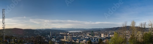 Large panorama of the city of Zurich in spring with the snowy Swiss Alps in the background from the Waid