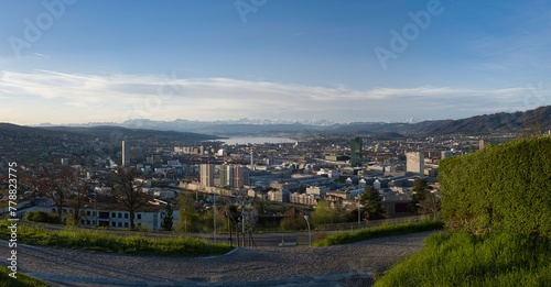 Large panorama of the city of Zurich in spring with the snowy Swiss Alps in the background from the Waid