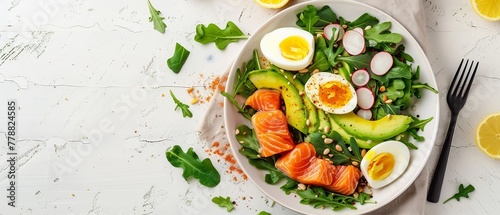 A nutritious bowl of salmon and avocado salad with boiled eggs greens