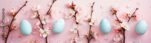 Pastel Easter eggs with delicate cherry blossoms arranged on a soft pink background.