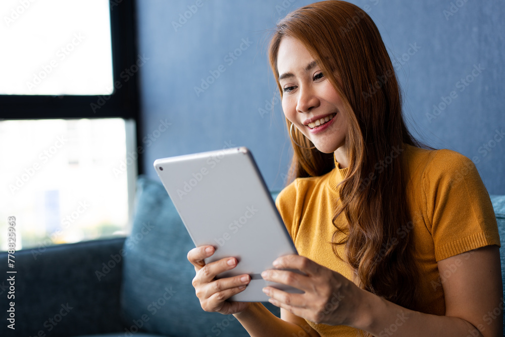 Portrait of Young attractive asian woman resting on sofa and using and looking at tablet pc in modern room communication and lifestyle concept. reading digital gadget at house. Portrait of Young attractive asian woman resting on sofa and using and looking at tablet pc in modern room communication and lifestyle concept. reading digital gadget at house.