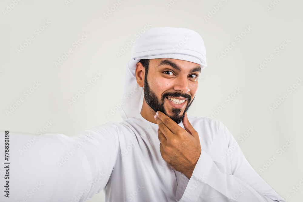 Handsome middle-eastern man wearing emirate traditional clothing portrait in studio Handsome middle-eastern man wearing emirate traditional clothing portrait in studio