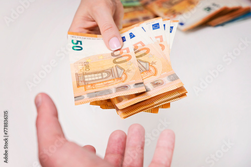 Human hand holding a bunch of Euros banknotes. Man giving money to a woman. Street economy, bribery, corruption, black market Urban lifestyle. Isolated on white background, close up shot.
