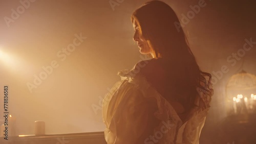 Woman in vintage dress looking away in a candlelit room with fog. Period drama concept with copy space for design and print. Cinematic portrait with atmospheric lighting.
