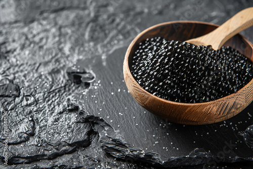Black sturgeon caviar, wooden bowl, dark stone texture. Healthy food