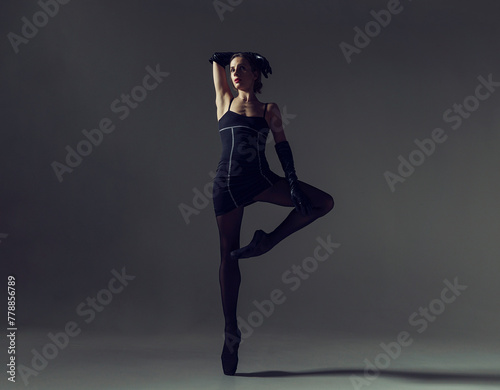 ballerina in total black style in a dress and tights poses silhouetted elements of ballet