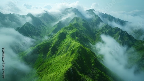  An aerial view of a mountain range covered in green grass and low-lying clouds in the foreground, with a blue sky in the background