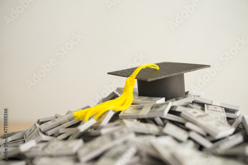 Graduation cap university or college degree on US dollars banknotes pile. Education expense budget plan of money saving, student loan or debt, personal loan, scholarship for studying abroad concept.
