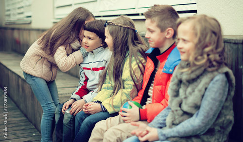 Girls and boys on bench playing games in yard photo