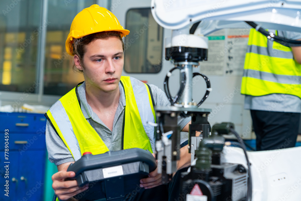 Manufacturing industry factory manufacturing technology concept. Professional male technician engineer in safety wear checking robotic machine arm system in production line for repair and maintenance. Manufacturing industry factory manufacturing technology concept. Professional male technician engineer in safety wear checking robotic machine arm system in production line for repair and maintenance.