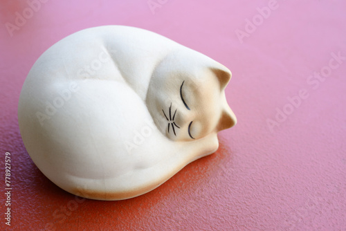Ceramic sleeping cat doll on the table, home and garden decoration object