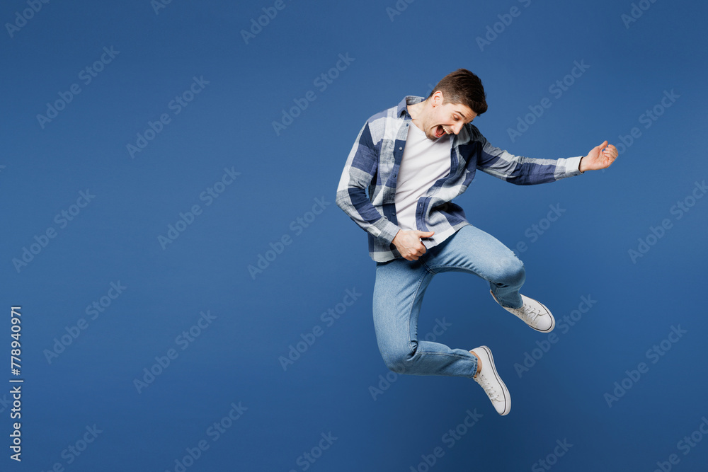 Full body singer happy young man he wear shirt white t-shirt casual clothes jump high pov play air guitar on stage sing song isolated on plain blue cyan background studio portrait. Lifestyle concept.