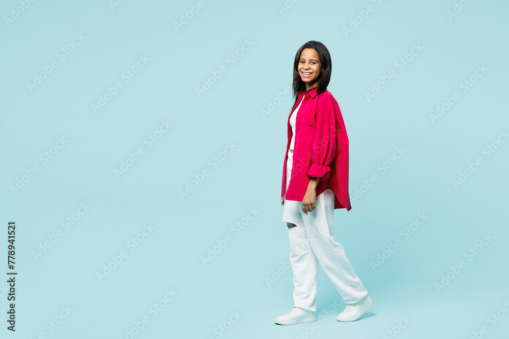 Full body side profile view happy little kid teen girl wear pink shirt white t-shirt look camera walking going isolated on plain pastel light blue cyan background studio. Childhood lifestyle concept. Full body side profile view happy little kid teen girl wear pink shirt white t-shirt look camera walking going isolated on plain pastel light blue cyan background studio. Childhood lifestyle concept.