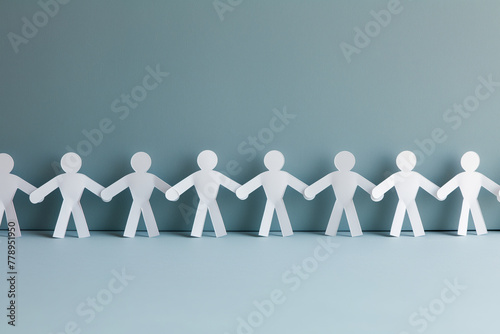 Paper human chain holding hands together on clean and clear pastel color background, teamwork concep