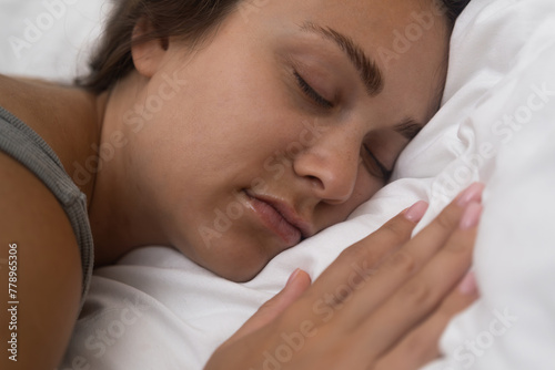 A weary woman sleeps facedown on a pillow, her exhaustion evident, though the position may contribute to facial wrinkles photo